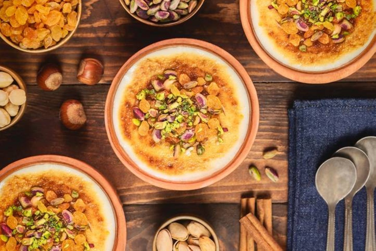 Arabic Cuisine; Traditional Egyptian dessert «Om Ali» or «Umm Ali» of soaked bread, milk and load of roasted nuts and raisins. Top view with close up.